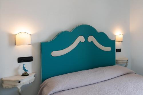 a bed with a blue headboard with a moustache on it at Palazzo Vingius in Minori