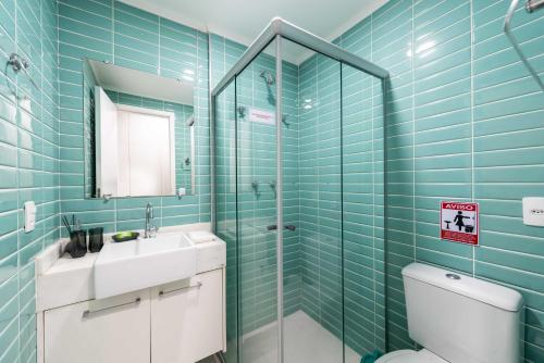 a bathroom with blue tiled walls and a toilet and a sink at Rover República in Sao Paulo