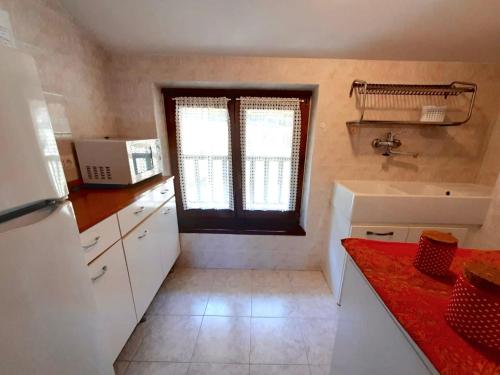 Elle comprend une petite cuisine avec un évier et une fenêtre. dans l'établissement Casa Maria, à Ledro