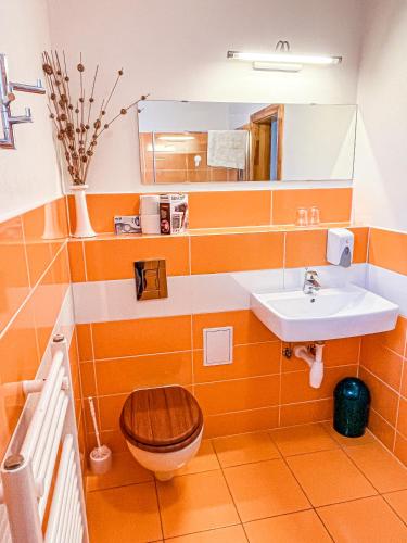 an orange bathroom with a toilet and a sink at Penzion Limba in Belá