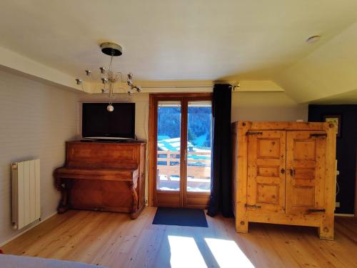 a room with a television and a piano and a door at Chambre d'hôtes Chalet AILLEURS in Molines-en-Queyras