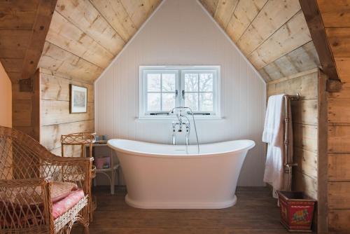 ein Badezimmer mit einer großen Badewanne im Dachgeschoss in der Unterkunft Bushes Oast by Bloom Stays in Sevenoaks