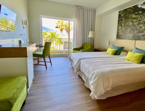 una camera d'albergo con 2 letti e una scrivania di Hotel Tigaiga a Puerto de la Cruz