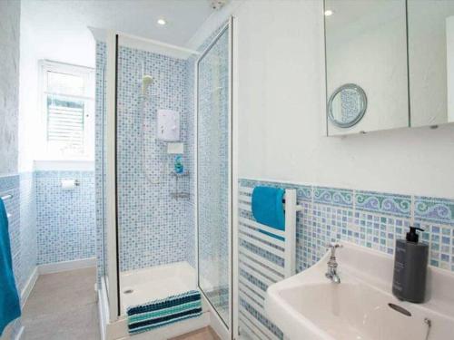 W wyłożonej niebieskimi kafelkami łazience znajduje się umywalka i prysznic. w obiekcie Detached period house in sought after location w mieście Torquay