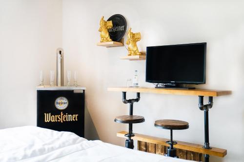 a bedroom with a bed and a tv and a desk at AiREA Hotel in Büren