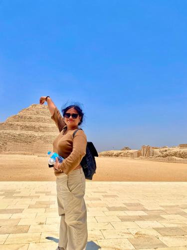 a woman is standing in front of the pyramids at New Museum Guest House, Pyramids View in Cairo