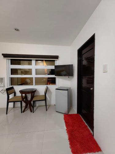 a living room with a table and chairs and a red rug at Hardrock Residences in Cabanatuan