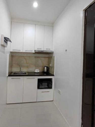 a kitchen with white cabinets and a black microwave at Hardrock Residences in Cabanatuan