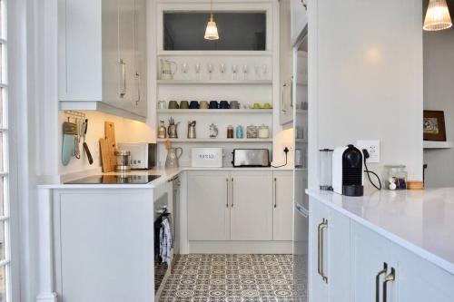 Una cocina blanca con gabinetes y electrodomésticos blancos. en Spacious 3 Bedroom Home Green Point, en Ciudad del Cabo