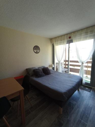 a bedroom with a bed and a table and a window at Appt 4 pers au Pla d' Adet, Résidence le Grand Stemm , station de ski Saint Lary in Saint-Lary-Soulan