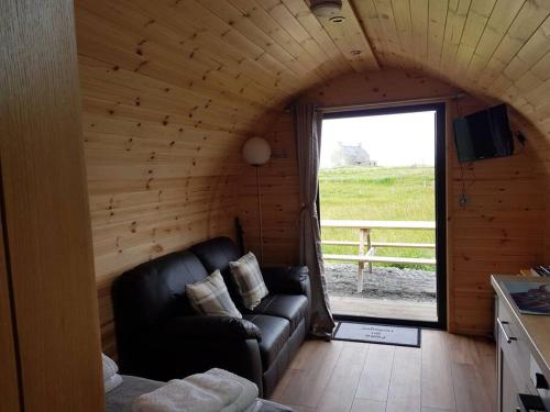 ein Wohnzimmer mit einem Sofa in einem Zimmer mit einem Fenster in der Unterkunft Hoilisgeir Self Catering Pod in Daliburgh