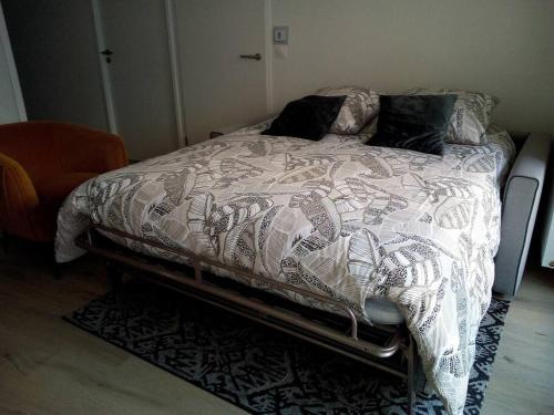 a bed with a comforter on it in a bedroom at Confortable T2 NEUF - RDC - 2/4 personnes in Mondeville