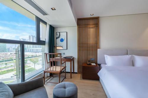 a bedroom with a bed and a chair and a window at Huawen Four Season Hotel in Zhaoqing