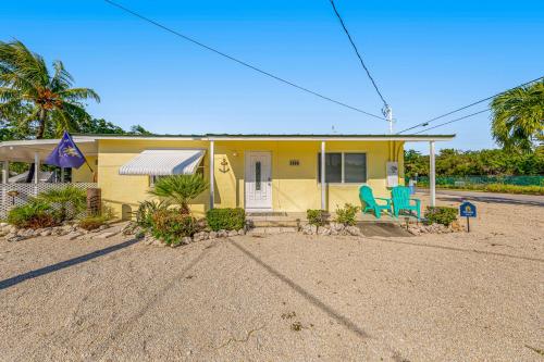 a yellow house with two blue chairs in front of it at Yellowtail House in Marathon
