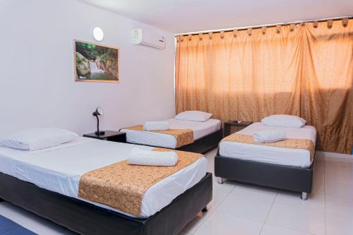 una camera da letto con tre letti e una finestra di Hotel Sol Inn Santa Marta a Santa Marta