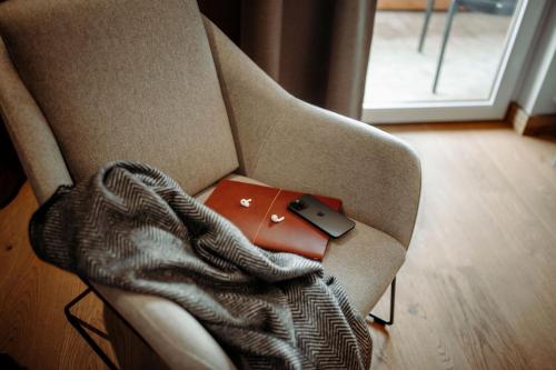 a red laptop sitting on a chair with a blanket at Alpina Alpendorf in Sankt Johann im Pongau