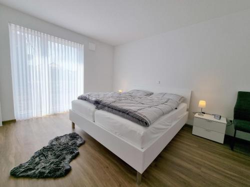 a white bedroom with a bed and a chair at Ferienwohnung Angela - a90191 in Walchum
