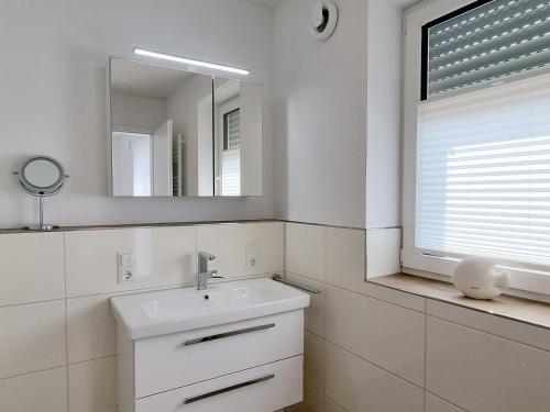 a white bathroom with a sink and a mirror at Ferienwohnung Angela - a90191 in Walchum