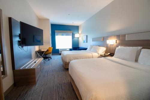 a hotel room with two beds and a flat screen tv at Holiday Inn Express Leland - Wilmington Area, an IHG Hotel in Leland