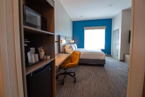 a hotel room with a bed and a desk with a chair at Holiday Inn Express Leland - Wilmington Area by IHG in Leland