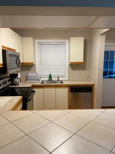 una cocina vacía con fregadero y microondas en Comfy Room Stay - Unit 1, en Kingston
