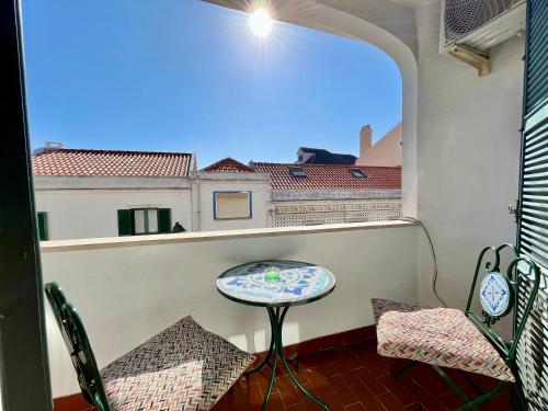 a balcony with a table and chairs and a window at Ljmonade Hostel in Cascais