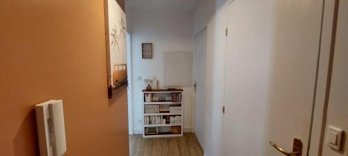 a hallway with a book shelf next to a door at Appartement Spacieux avec Parking proche MER in Saint-Nazaire