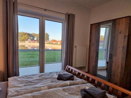 a bedroom with a bed and a large window at Ferienhaus Seebrise - a90185 in Walchum