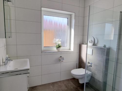 a white bathroom with a toilet and a window at Ferienhaus Seebrise - a90185 in Walchum