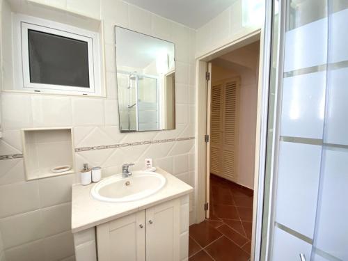 een witte badkamer met een wastafel en een spiegel bij Albufeira Quinta da Balaia Garden by Homing in Albufeira