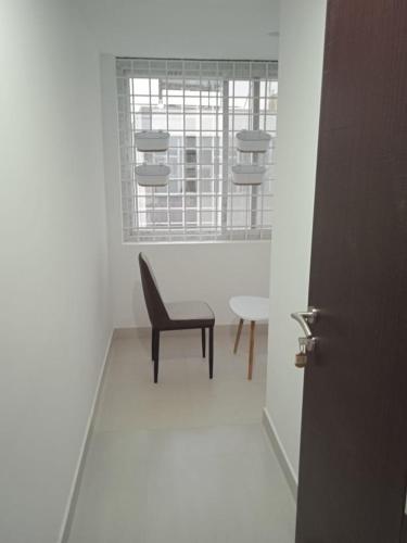 une chaise et une table dans une chambre avec fenêtre dans l'établissement Purple suites, à Ranipet