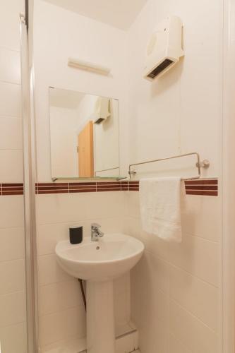 a white bathroom with a sink and a mirror at GuestReady - Modern stay by Pheonix Park in Dublin