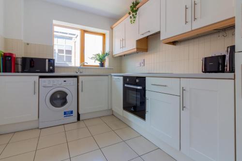 a kitchen with white cabinets and a washer and dryer at GuestReady - Modern stay by Pheonix Park in Dublin