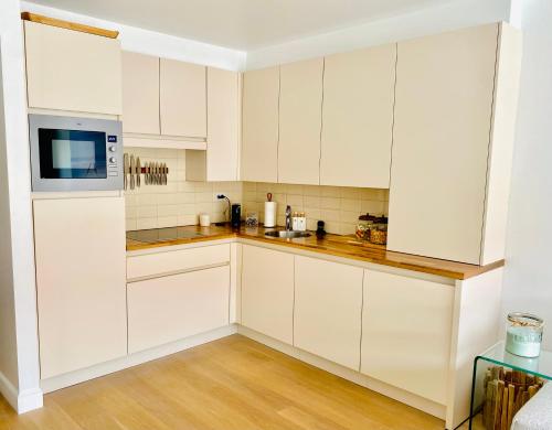 eine Küche mit weißen Schränken und einer Mikrowelle in der Unterkunft Appartement moderne 2 chambres et grand balcon in Knokke-Heist