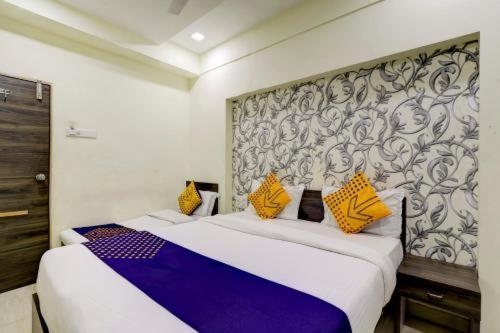 Hotel Gitanjali في أحمد آباد: غرفة نوم بسرير كبير مع مخدات صفراء