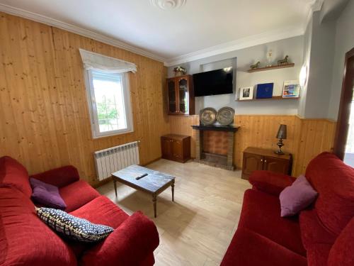 a living room with a red couch and a fireplace at Chalet Rialeda in Oleiros