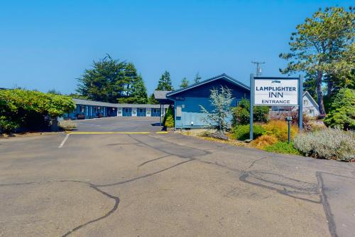 an empty parking lot with a sign in front of a motel at Lamplighter Inn - Tropical Fish Cove and Octopus Encounter in Bandon