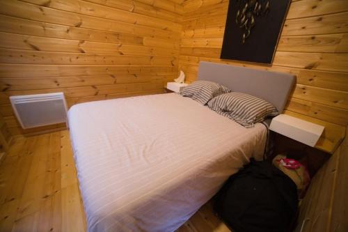 - une chambre avec un lit blanc dans un mur en bois dans l'établissement Cottage autour de l'étang 80, à Bourbourg