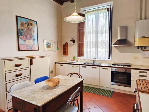 eine Küche mit weißen Schränken und einem Tisch mit einer Schüssel darauf in der Unterkunft Villa Gattoni Cattaneo - Appartamento Le Magnolie in Lardara