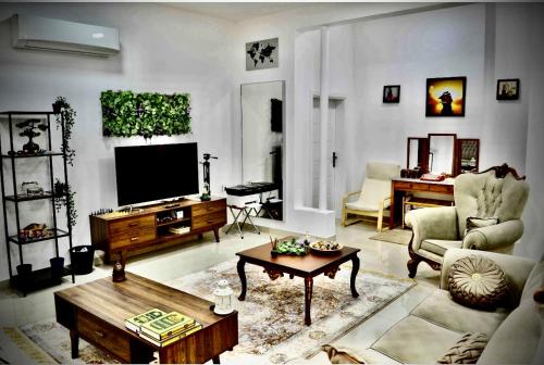 een woonkamer met een tv en een bank en een tafel bij نزل الشاطئ in Ḩayl Āl ‘Umayr