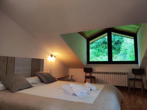 a bedroom with a large white bed with a window at Allotjaments el Pont in Camprodon