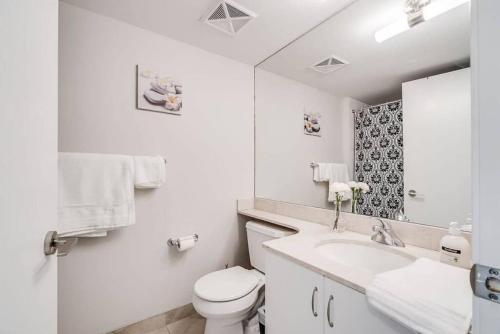 a white bathroom with a toilet and a sink at Beautiful 1BD 1BA Condo Lake and City Views in Toronto