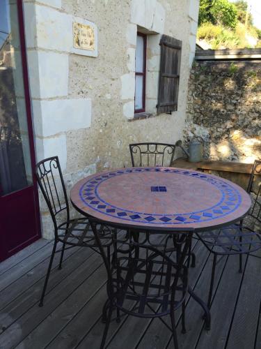 a metal table and chairs on a deck at Gîte semi-troglodytique du Vieux Chai de Trôo in Trôo