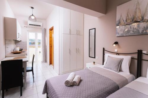 a bedroom with two beds and a desk and a kitchen at Filia Apartments in Pitsidia
