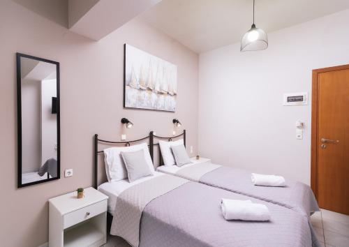 two beds in a white bedroom with a mirror at Filia Apartments in Pitsidia