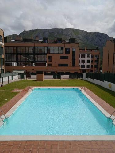 a large blue swimming pool in front of a building at Apartamento L' Espumeru in Posada de Llanes