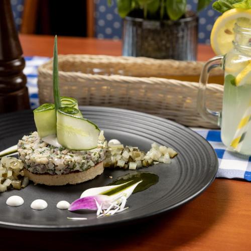 a black plate with a piece of food on a table at Hotel Diamond w Białym Dworku in Rumia