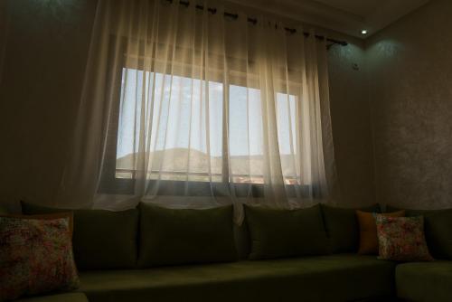 - un canapé dans le salon doté d'une fenêtre dans l'établissement Ayour appartement, à Azrou