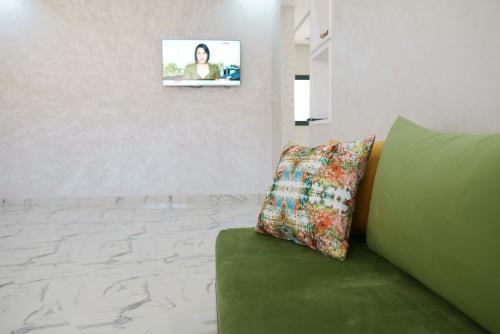 - un canapé vert avec un oreiller et une photo sur le mur dans l'établissement Ayour appartement, à Azrou