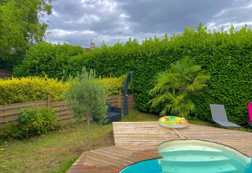 a backyard with a wooden table and a swimming pool at L'Aparenthese - Aux portes de Fontainebleau in Voulx